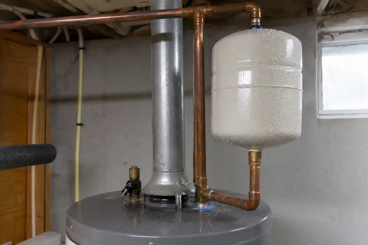 Condensation beads on water heater piping that can mimic a bottom leak under the tank
