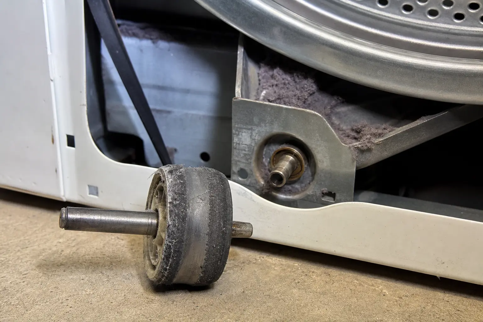 Worn dryer drum support roller with dust and flat wear near the open dryer support bracket