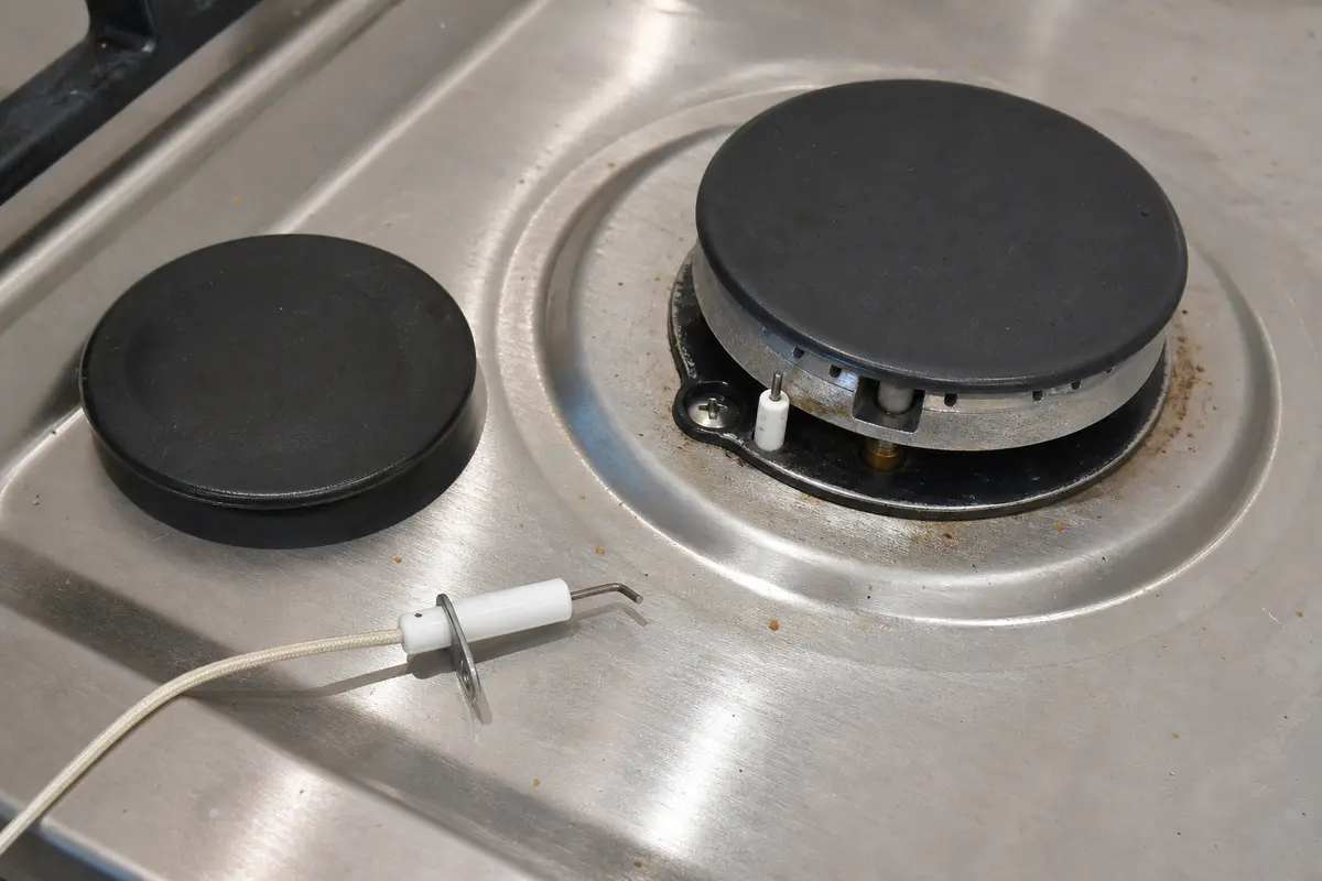 Cooktop spark igniter closeup showing the ceramic body and electrode tip to inspect before replacement