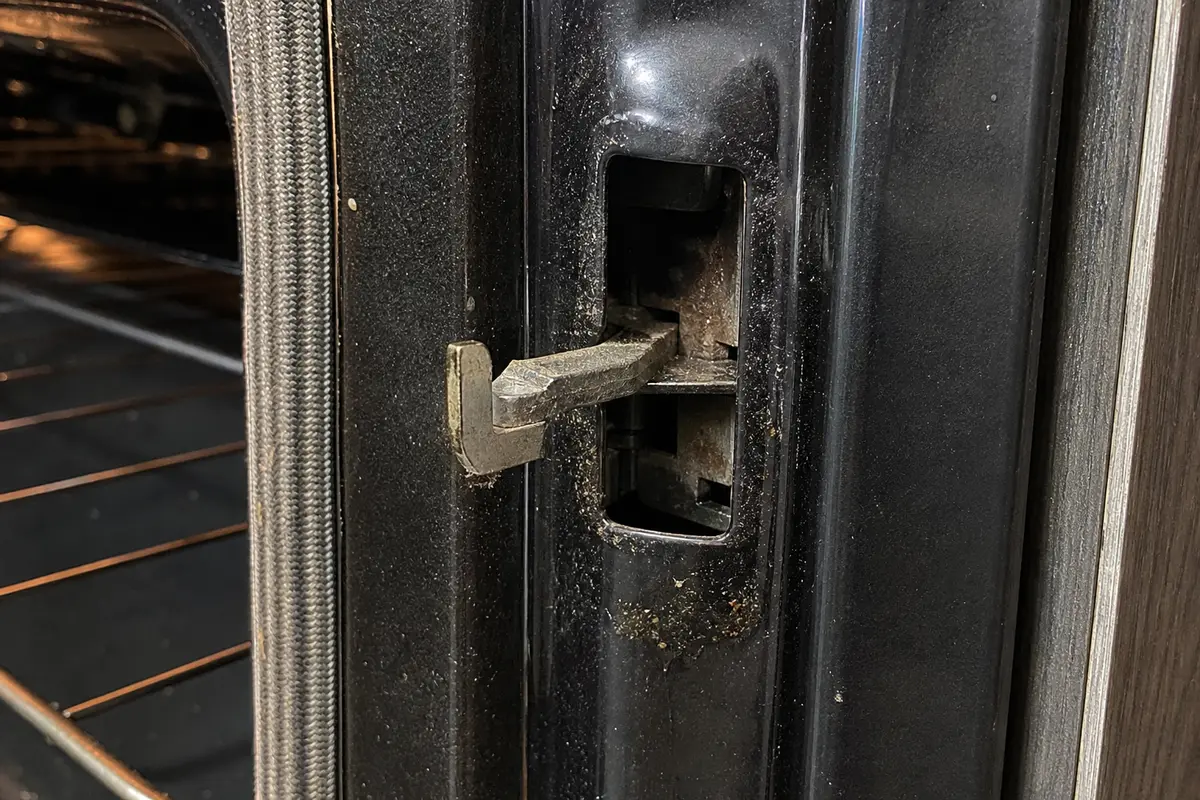 Oven door latch slot with a latch arm sitting halfway across the opening