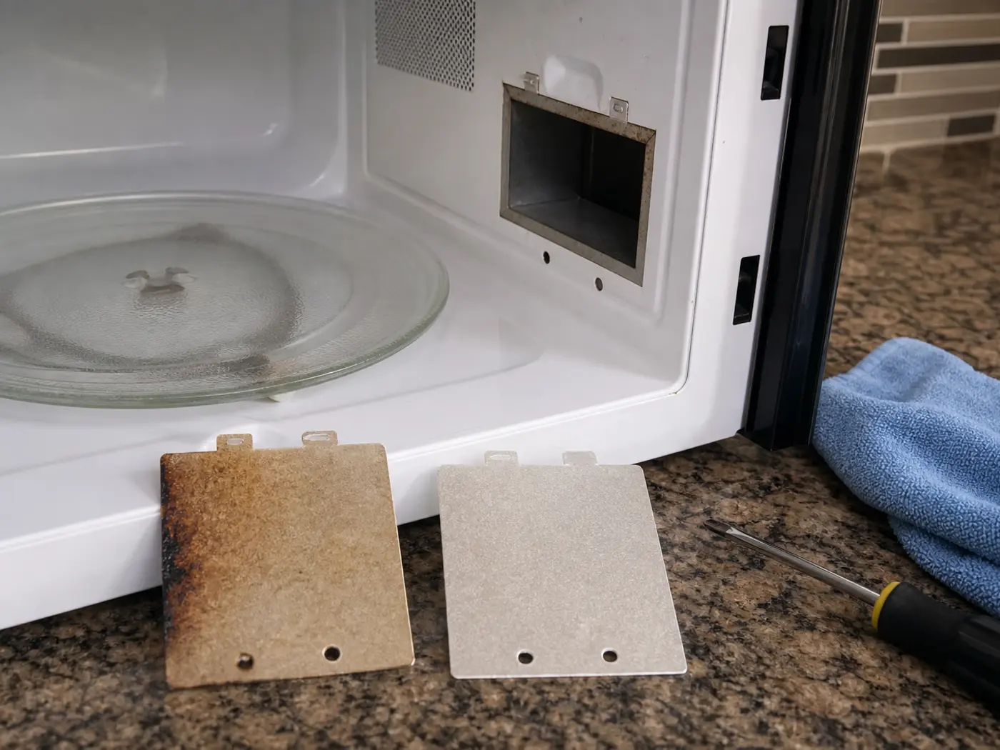 Old burned microwave waveguide cover beside a matching new mica cover at the open cavity