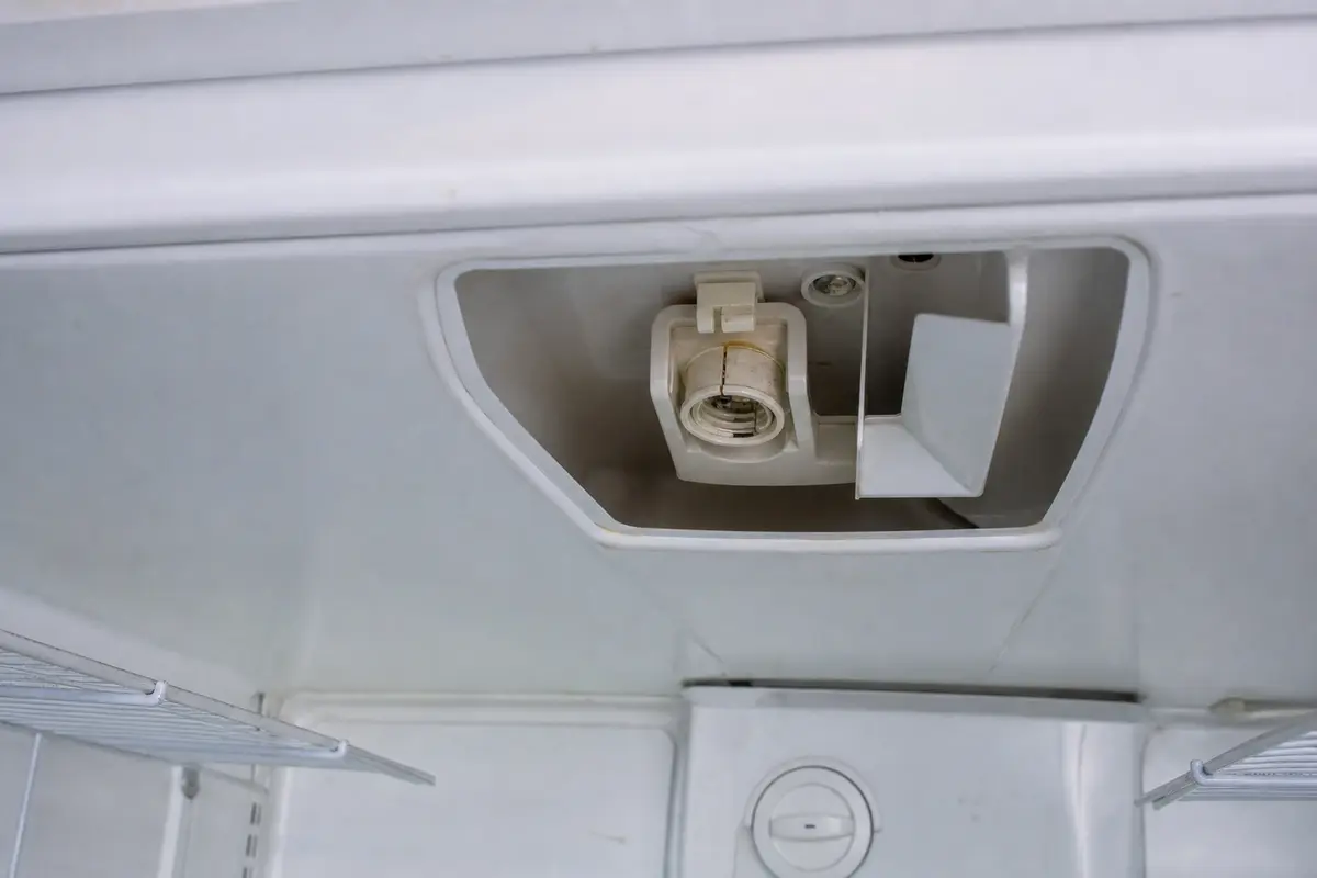 refrigerator light socket with visible heat damage before replacement