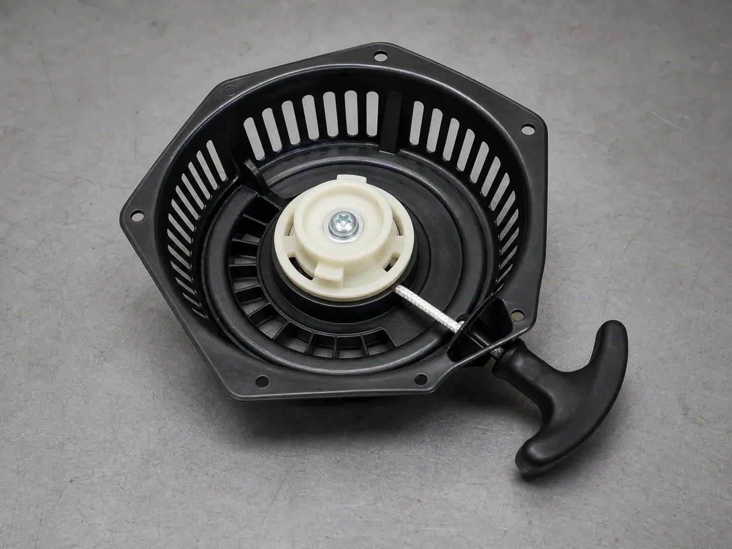 Pressure washer recoil starter assembly showing rope handle, housing, pulley area, and mounting holes
