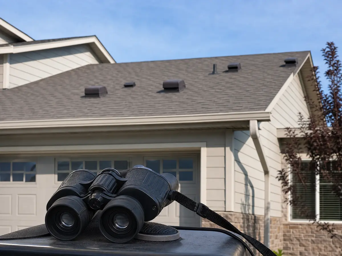 Inspection binoculars used from the ground to check an attic vent after wind-blown snow