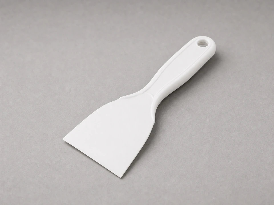 Flat plastic scraper for lifting soap buildup without scratching shower glass